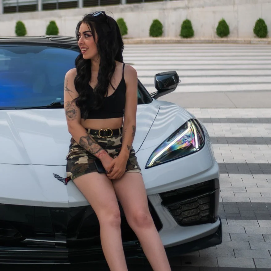 Abby Smith sitting on the hood of a white Corvette