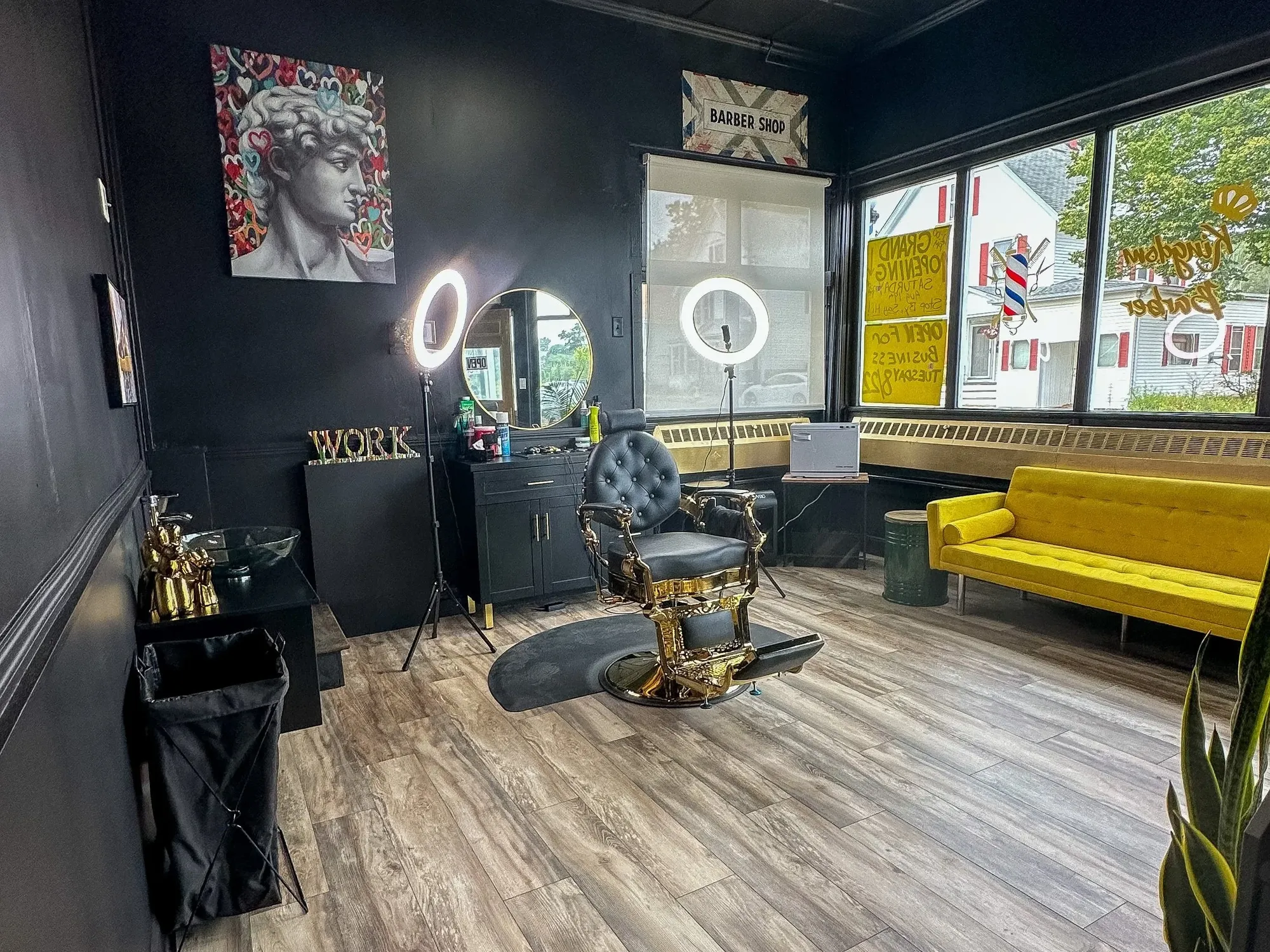 Inside Kingdom Barber — matte black walls, gold barber chair, ring lights and the mustard sofa