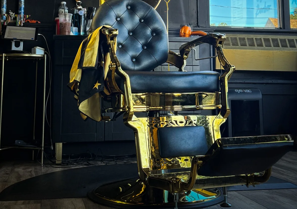 The gold-and-black tufted barber chair catching evening light