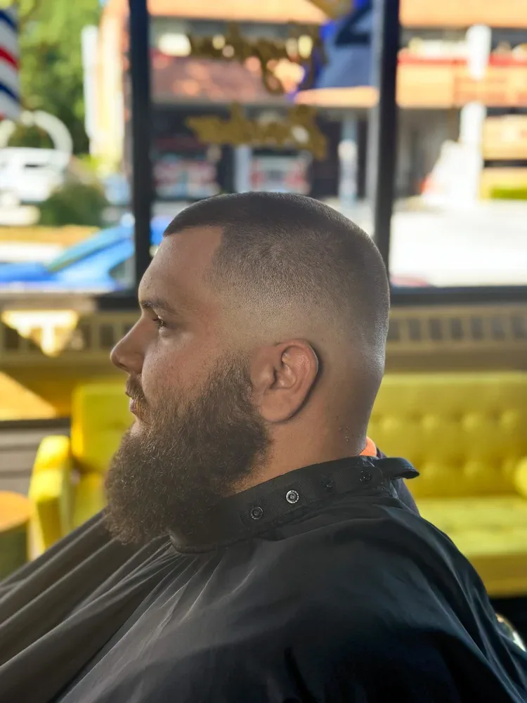 Bald fade blended into a full beard, side profile